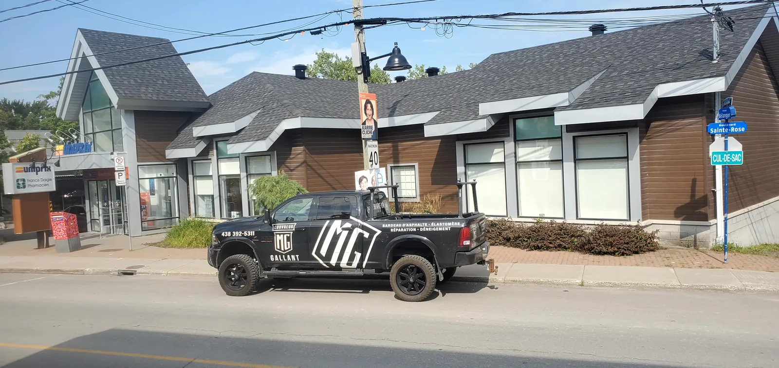 Camion MG Gallant devant un bâtiment commercial à la toiture fraîchement refaite