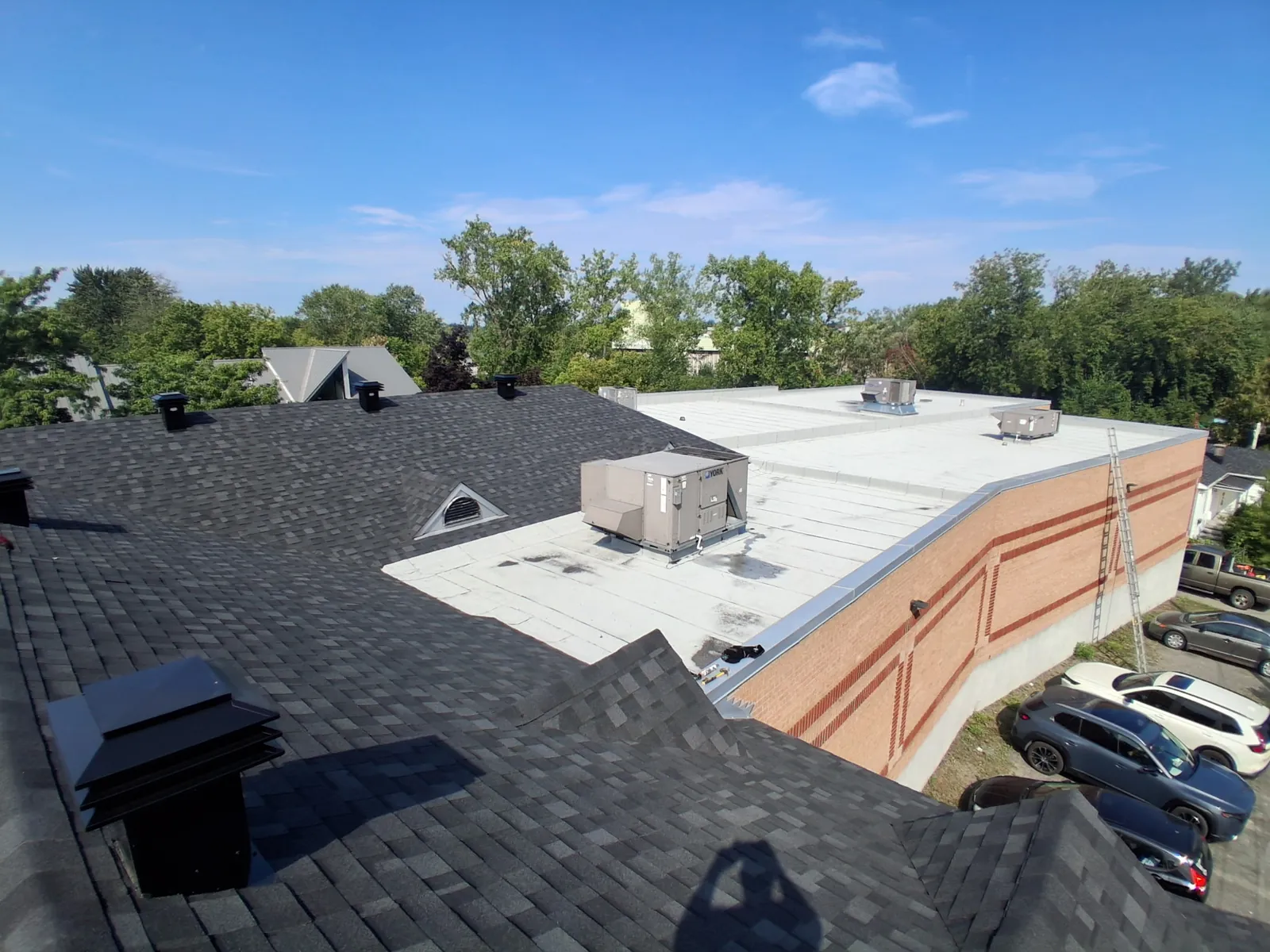 Bâtiment commercial: toiture en bardeau charbon et toit plat en membrane blanche avec unités de ventilation, chantier MG Gallant